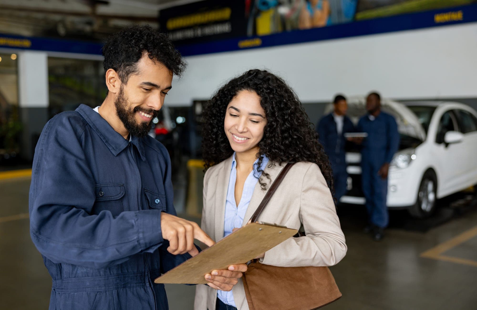 A service advisor and a customer reviewing a repair estimate together in an auto shop